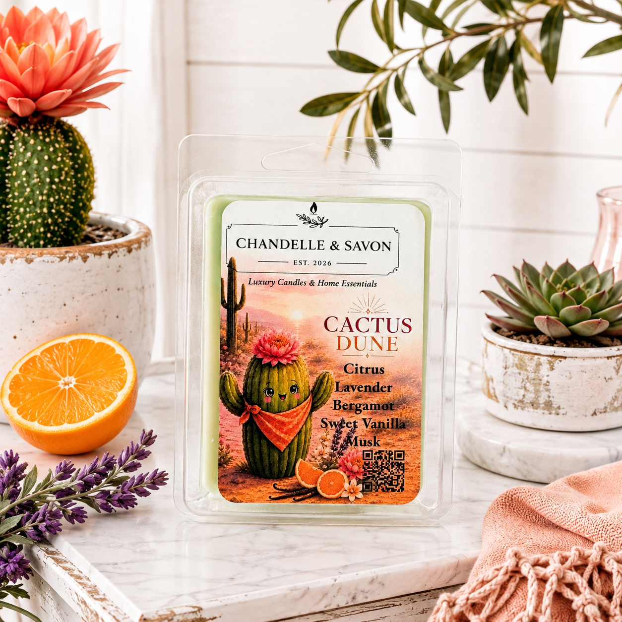 Chandel & Savon Cactus Dune scented wax melts in a clear clamshell package, styled on a white marble surface with a cactus, orange slice, lavender sprigs, and succulents.
