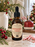 Chandelle & Savon Peppermint Twist diffuser oil in an amber glass dropper bottle, styled on a rustic table with Christmas decorations, candy canes, and a red diffuser in the background.