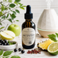 A bottle of Chandelille & Savion Ascendant Style: Blackcurrant + Bergamot Pineapple + Patchouli ultra sonic diffuser oil, styled with fresh fruits, berries, mint, and a diffuser in the background.