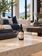 An amber glass dropper bottle labeled 'Midnight Ice' sits on a light beige stone countertop in a modern living room setting with a sofa, pillows, and large windows in the background.