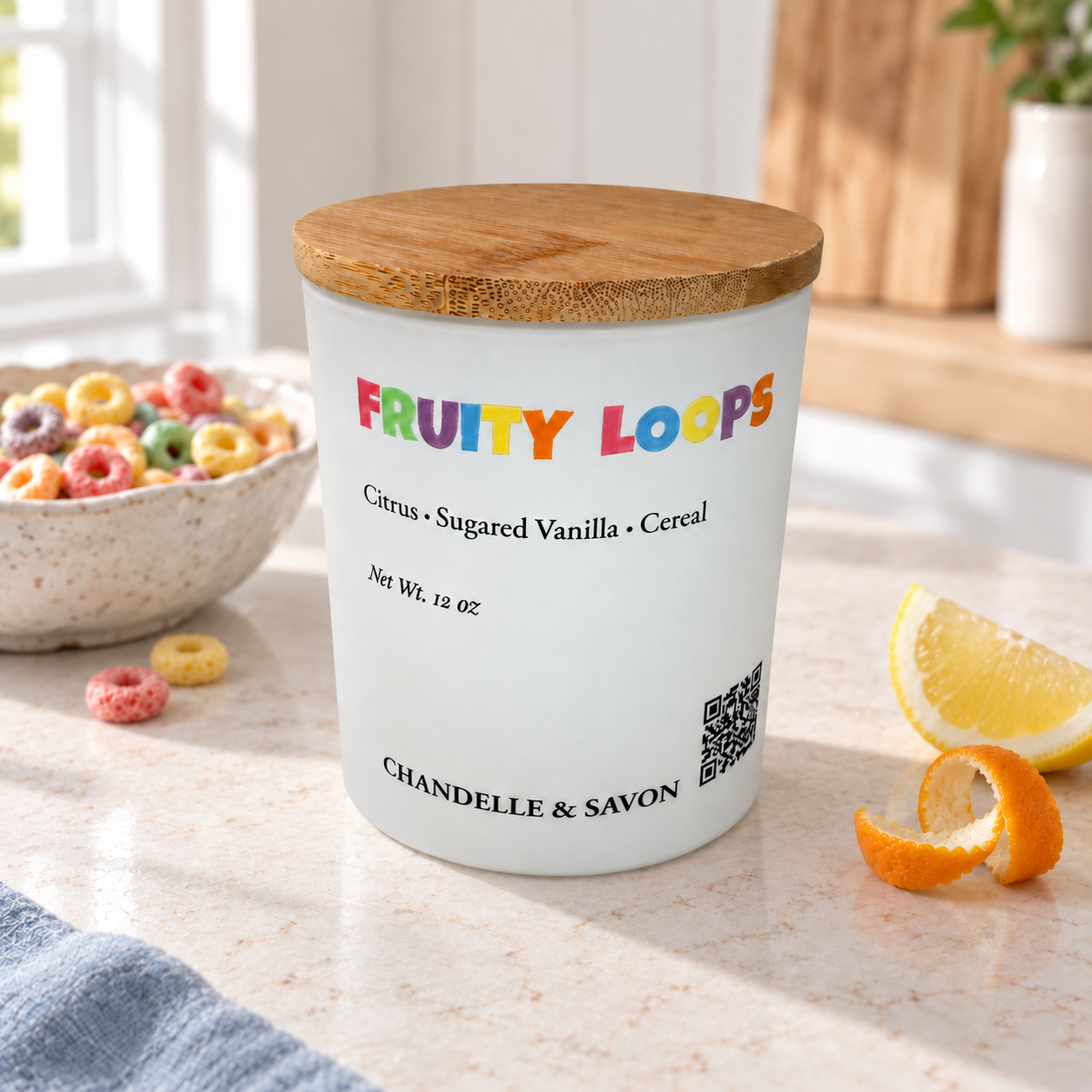 A frosted glass jar candle with a bamboo lid sits on a kitchen counter. The label reads 'FRUITY LOOPS' in colorful letters and 'Citrus • Sugared Vanilla • Cereal' with 'CHANDELL & SAVON' at the bottom.
