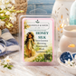 Chandelier & Savon Honey Silk luxury candle wax melts in a clear plastic clamshell package, displayed on a rustic white wooden table surrounded by floral and candle props.