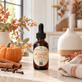A bottle of Chandelle & Savon Pumpkin Spice diffuser oil with a black dropper cap, set on a stone countertop with a small pumpkin, cinnamon sticks, cloves, and a warm, softly blurred kitchen background.