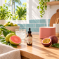 A small amber dropper bottle labeled RIO RUSH sits on a wooden countertop in a bright kitchen setting, surrounded by guava fruit, a glass of iced drink, a pink diffuser, and other fresh ingredients.