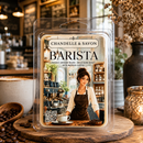A clear plastic clamshell package labeled 'Chandelle & Savon Barista' stands on a wooden board in a coffee shop setting. The front label shows a woman in a cafe with coffee beans, a cup, and text describing freshly brewed coffee.