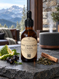 An amber glass dropper bottle labeled Chandelble & Savon Steel Mountain Creek, styled on a dark stone surface with mint, berries, and a cinnamon stick, with a blurred mountain and indoor setting in the background.