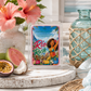 Chandelle & Savon Rio Rush wax melts in a clear clamshell package, styled on a white wooden board with pink hibiscus flowers, a blue glass bottle, and fruit in a bright, airy setting.