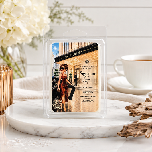 A packaged wax melt or scented melt product labeled 'Signature Spa' by Chandelle & Savon, shown in a clear plastic clamshell on a marble tray with spa-themed props including flowers, a cup of tea, and driftwood.