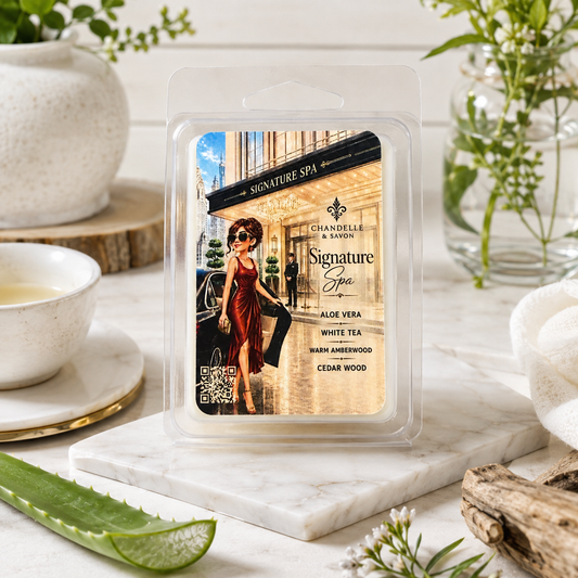 A packaged wax melt or scented melt product in a clear plastic clamshell package, standing on a white marble tray. The front label reads 'Signature Spa' and 'Chandelle & Savon,' with scent notes 'Aloe Vera,' 'White Tea,' 'Sarin Amherwood,' and 'Cedar Wood.